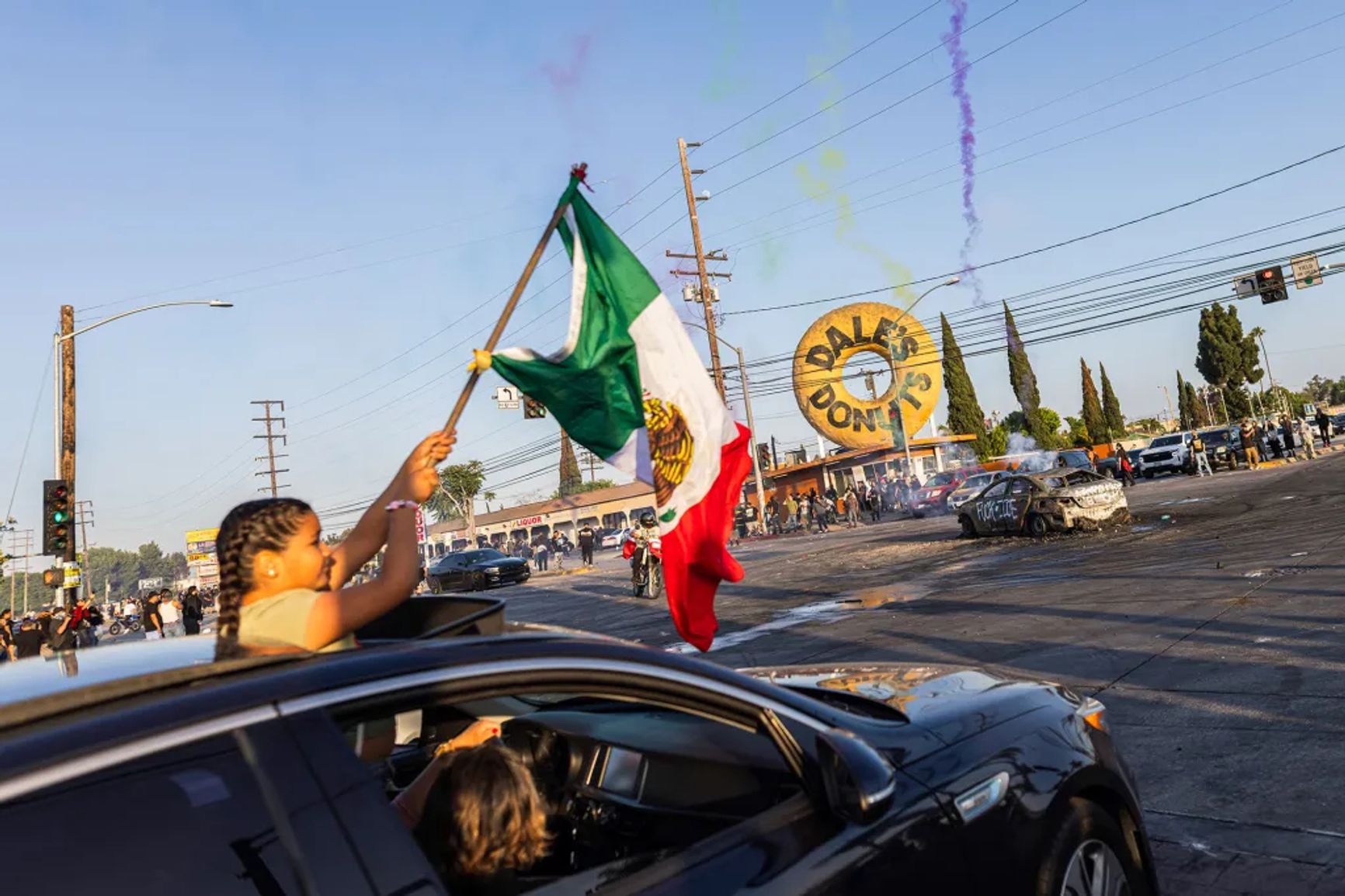 A girl waves a Mexican flag outside of a car during protests against immigration raids in Compton on June 7, 2025.